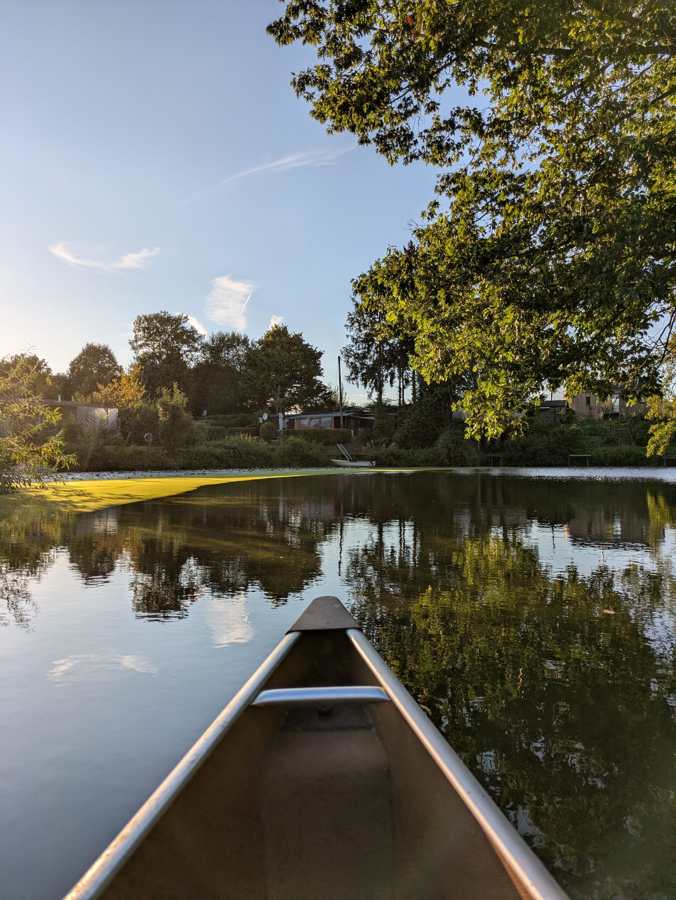 Blick vom Kanu über die spiegelglatte Werse im Abendlicht