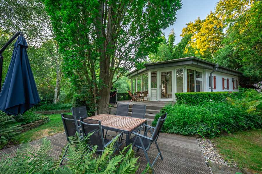 Holzdeck mit Esstisch, Grill und Blick in den Wintergarten