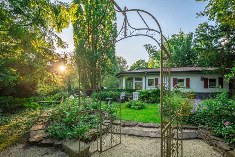 Schmiedeeiserner Rosenbogen im Garten in der Abendsonne