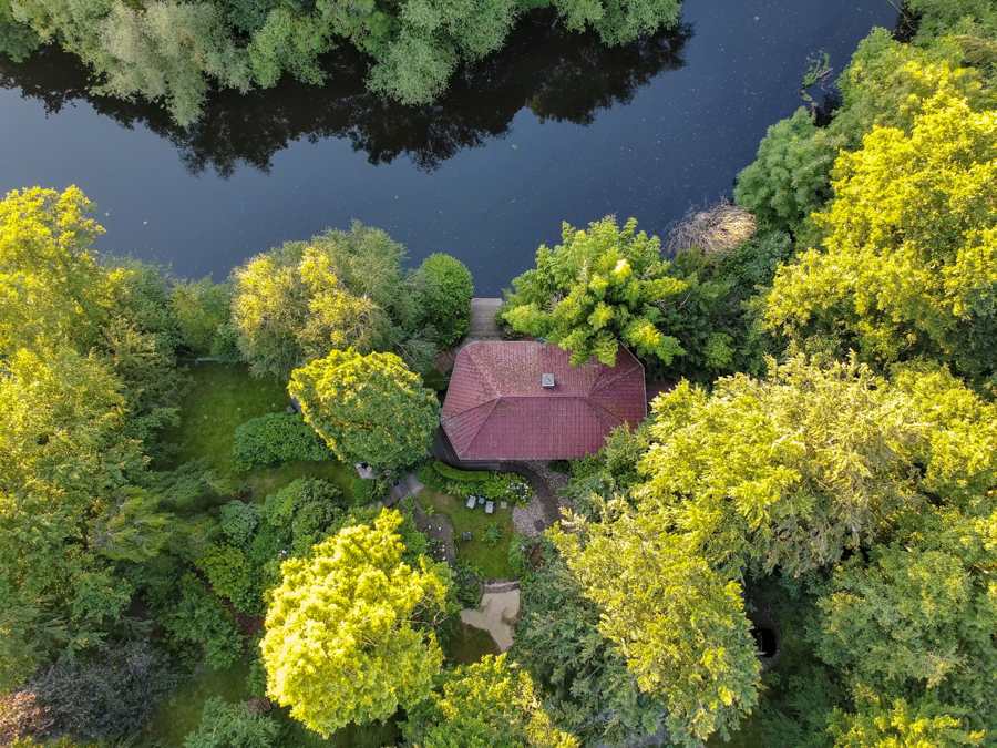 Das Wersehaus von oben: rotes Dach zwischen Baumkronen direkt an der Werse